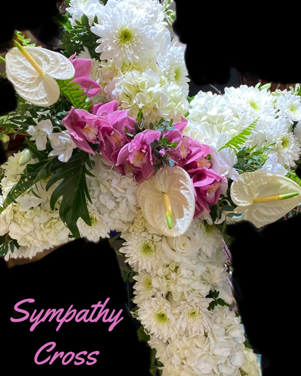Sympathy cross covered in white flowers with pink orchids