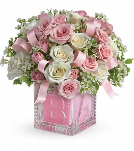 Pink and white rose arrangement in a glass vase with ribbon
