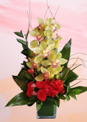 Red roses and yellow orchids in a glass vase