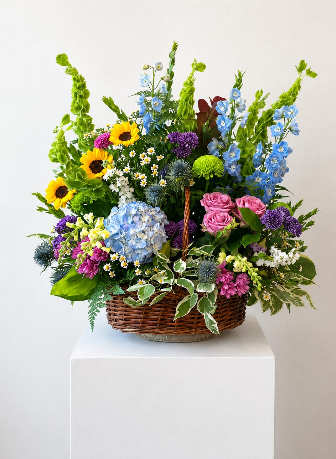 Mixed flower basket with sunflowers, blue hydrangea, pink roses, and purple blooms