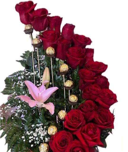 Red roses with pink lilies and chocolate truffles in a floral arrangement