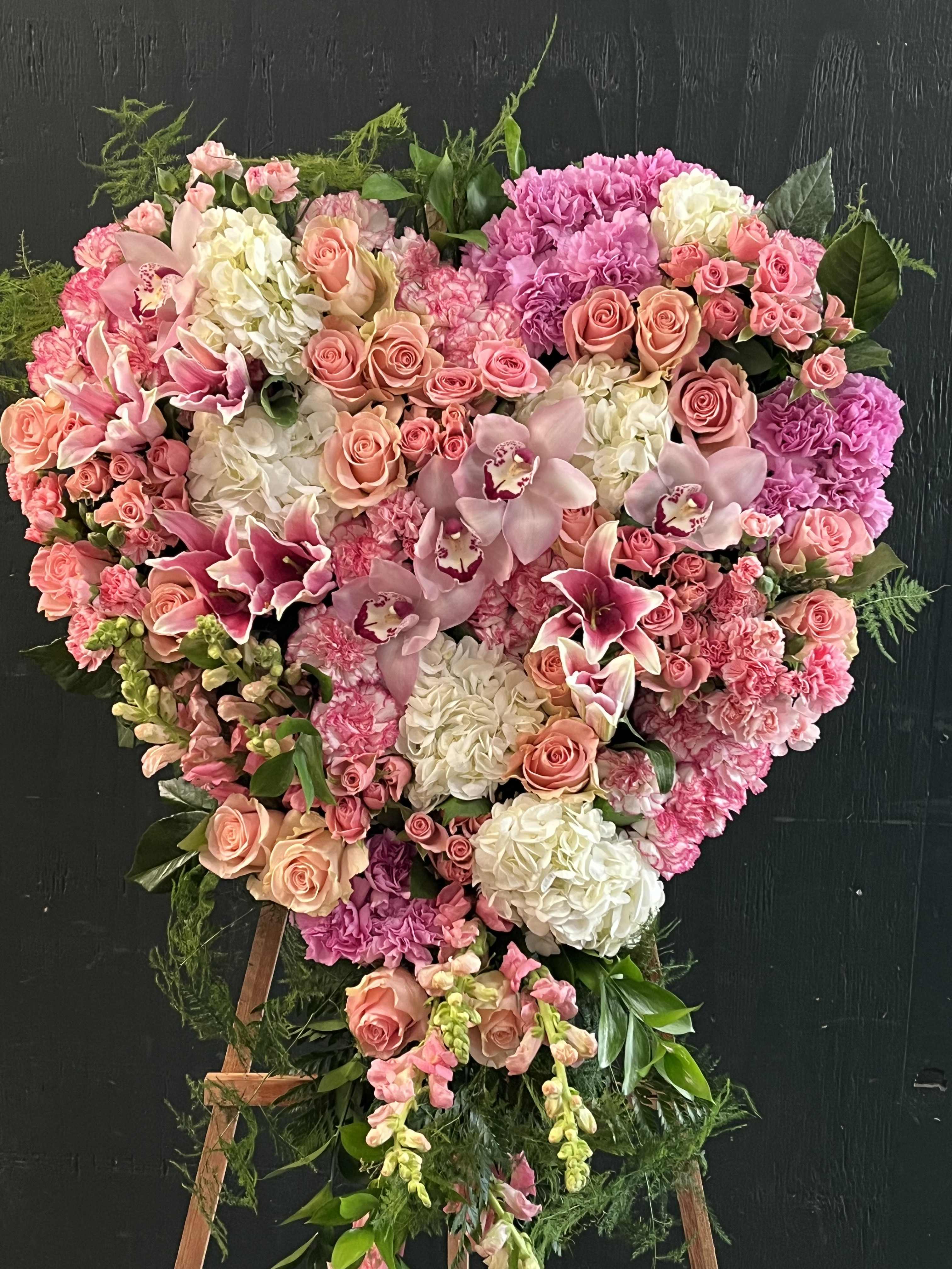 Heart-shaped floral standing arrangement in pink, peach, and white blooms