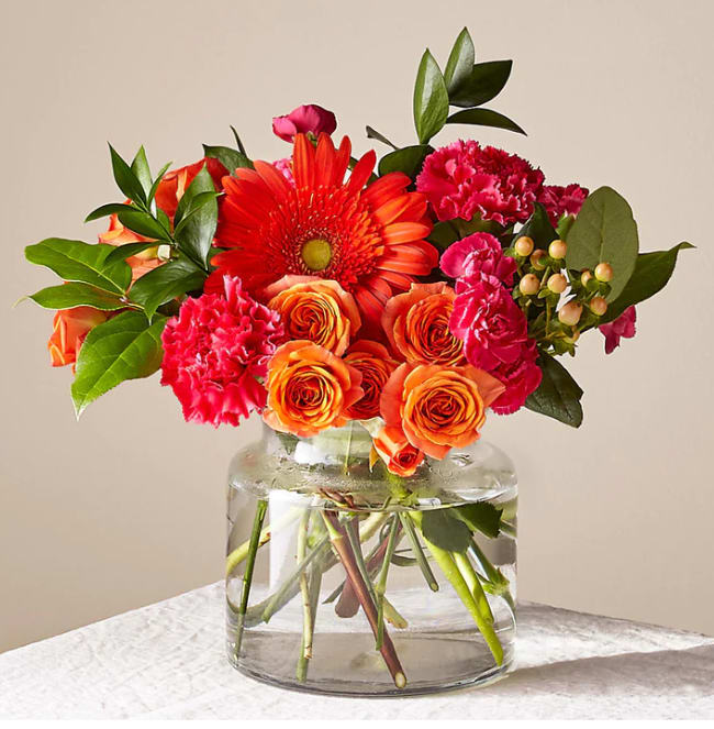 Orange and pink flowers arranged in a clear glass vase