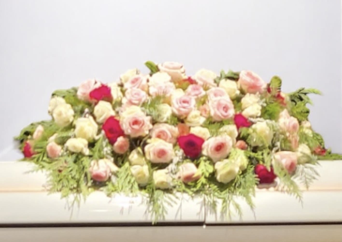 Low arrangement of pink and white roses with greenery
