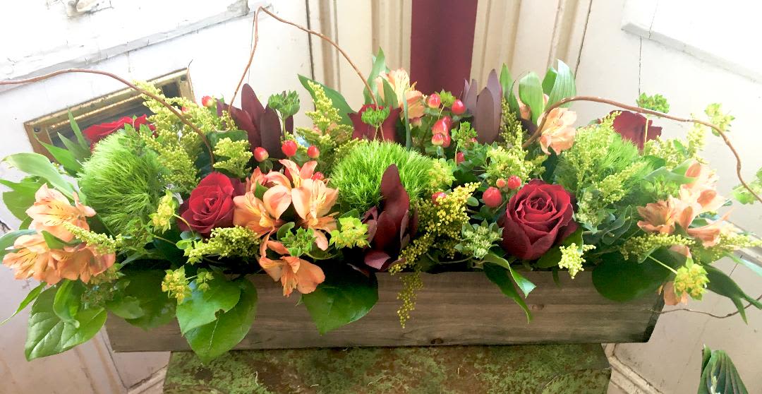 Rectangular floral arrangement with red roses and peach flowers in a wooden box