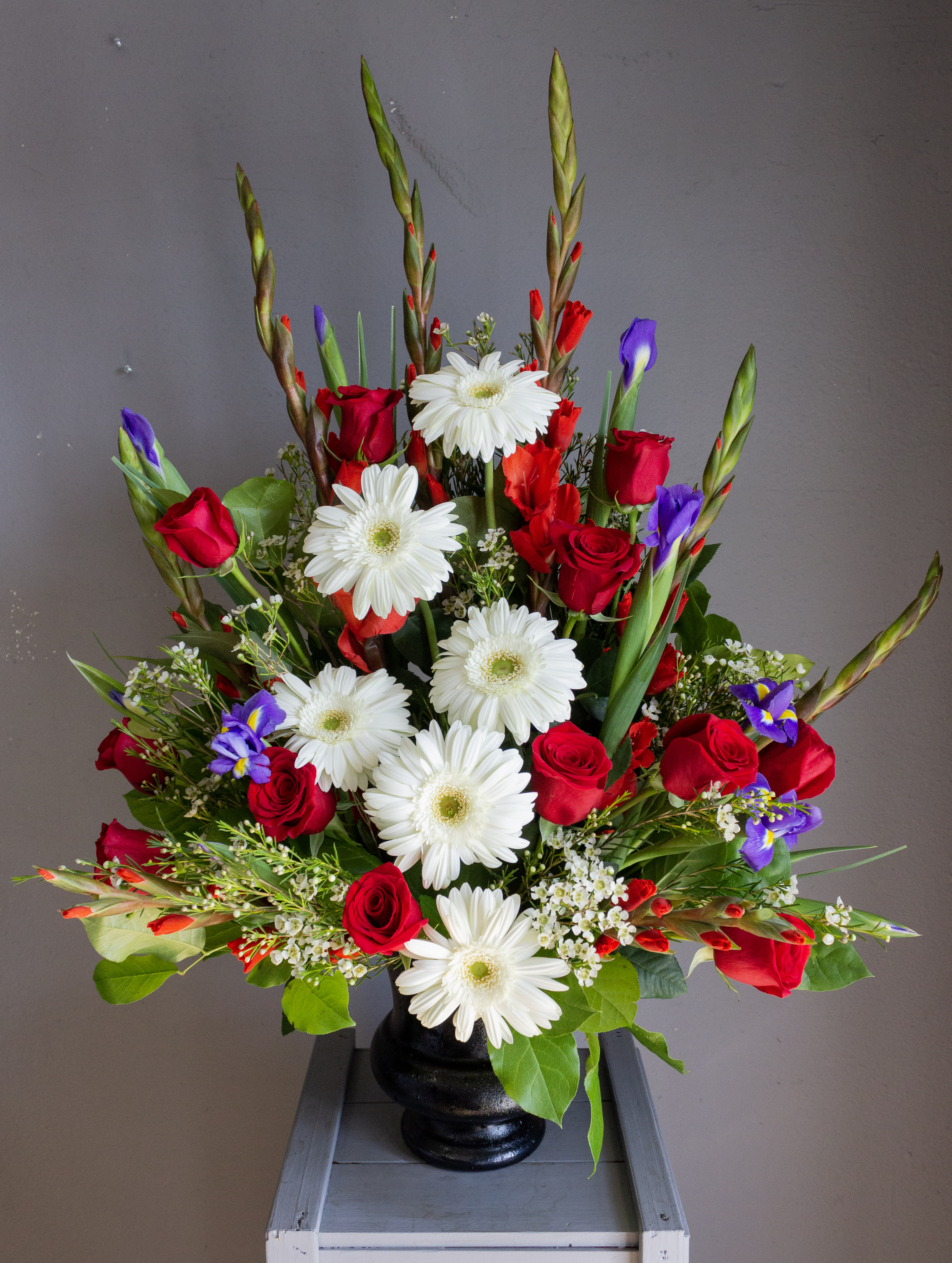 Red roses and white daisies in a black vase