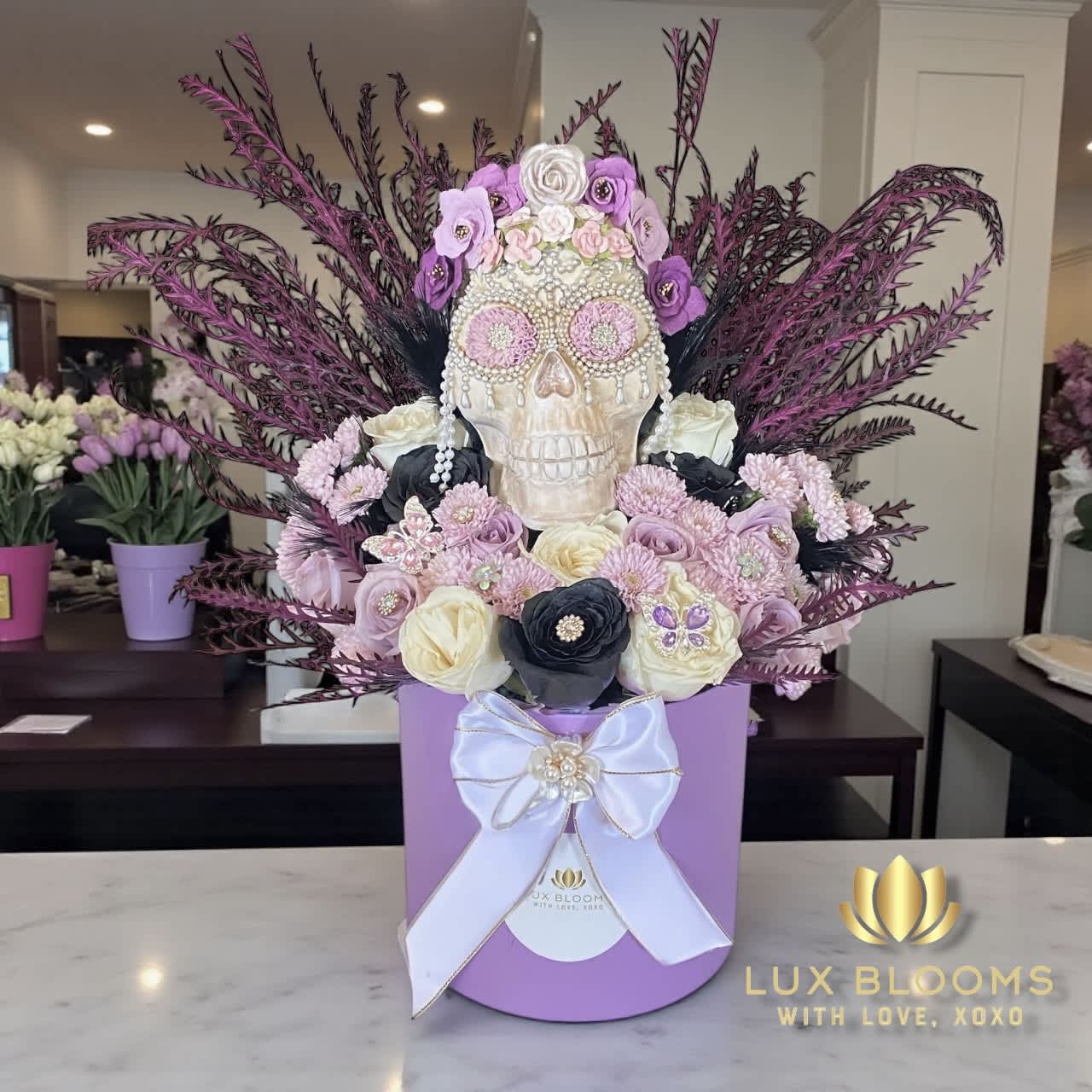 Decorative skull arrangement with purple and white flowers in a lavender box