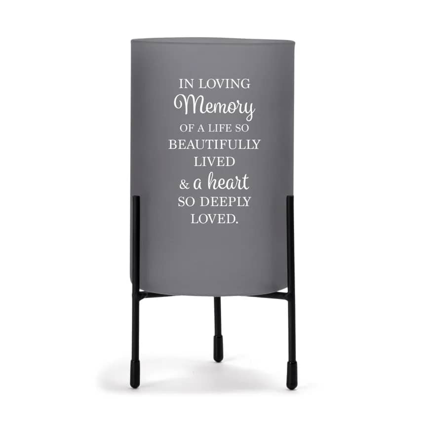 In Loving Memory Hurricane - This hurricane style glass candle stand is a beautiful way to illuminate and convey a heartfelt message of condolence. Charcoal grey color glass is decorated with a sentiment on the outside. Inside is room for a pillar style candle OR fresh flowers. Holder nestles in its own black metal stand with padded feet to protect furniture. Overall size of holder in stand is 8" high x 4" diameter width.   Words on holder: In loving memory of a life so beautifully lived &amp; a heart so deeply loved.  Upgrade options: Add flowers OR add candle and flowers!