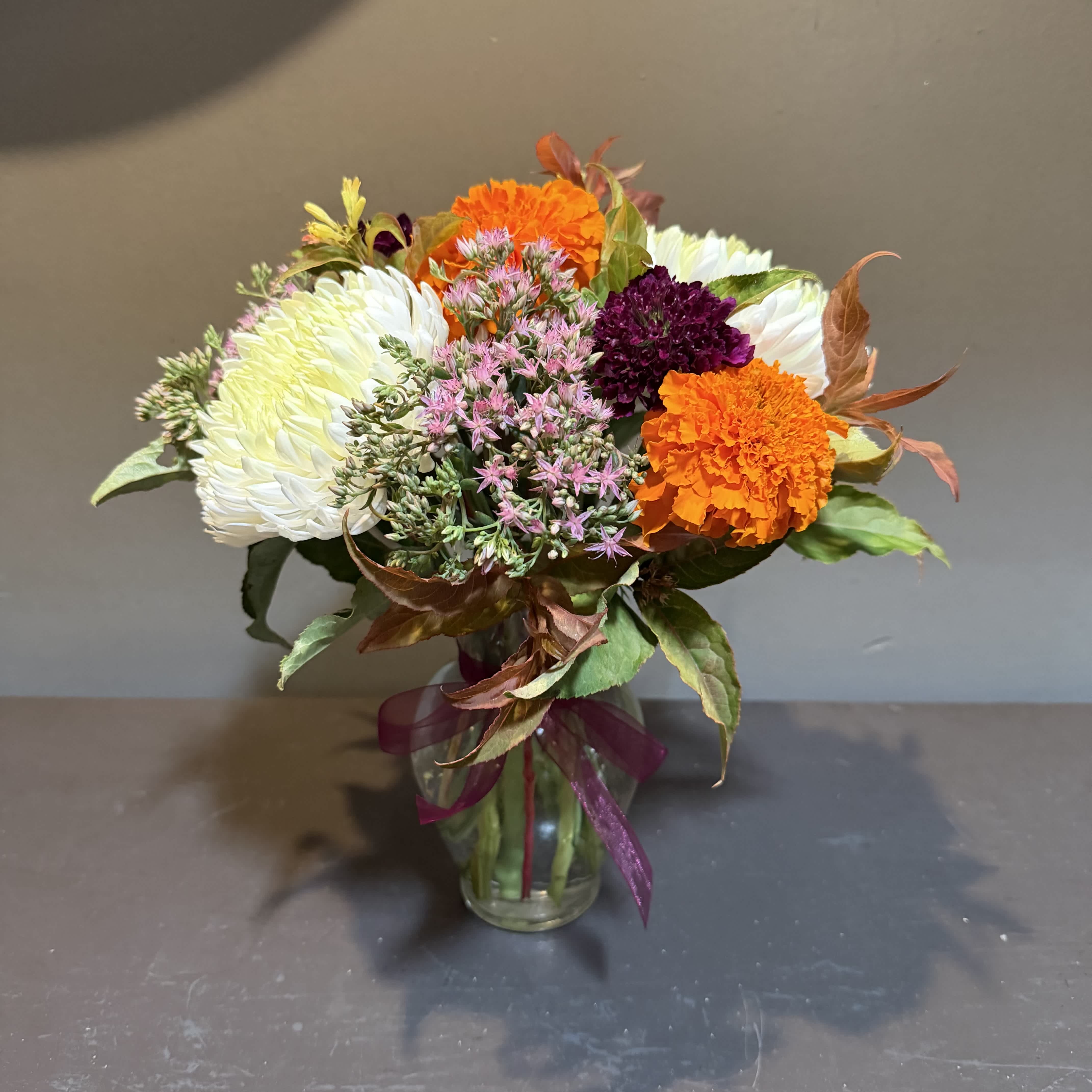 Mixed bouquet of white, orange, and purple flowers in a glass vase
