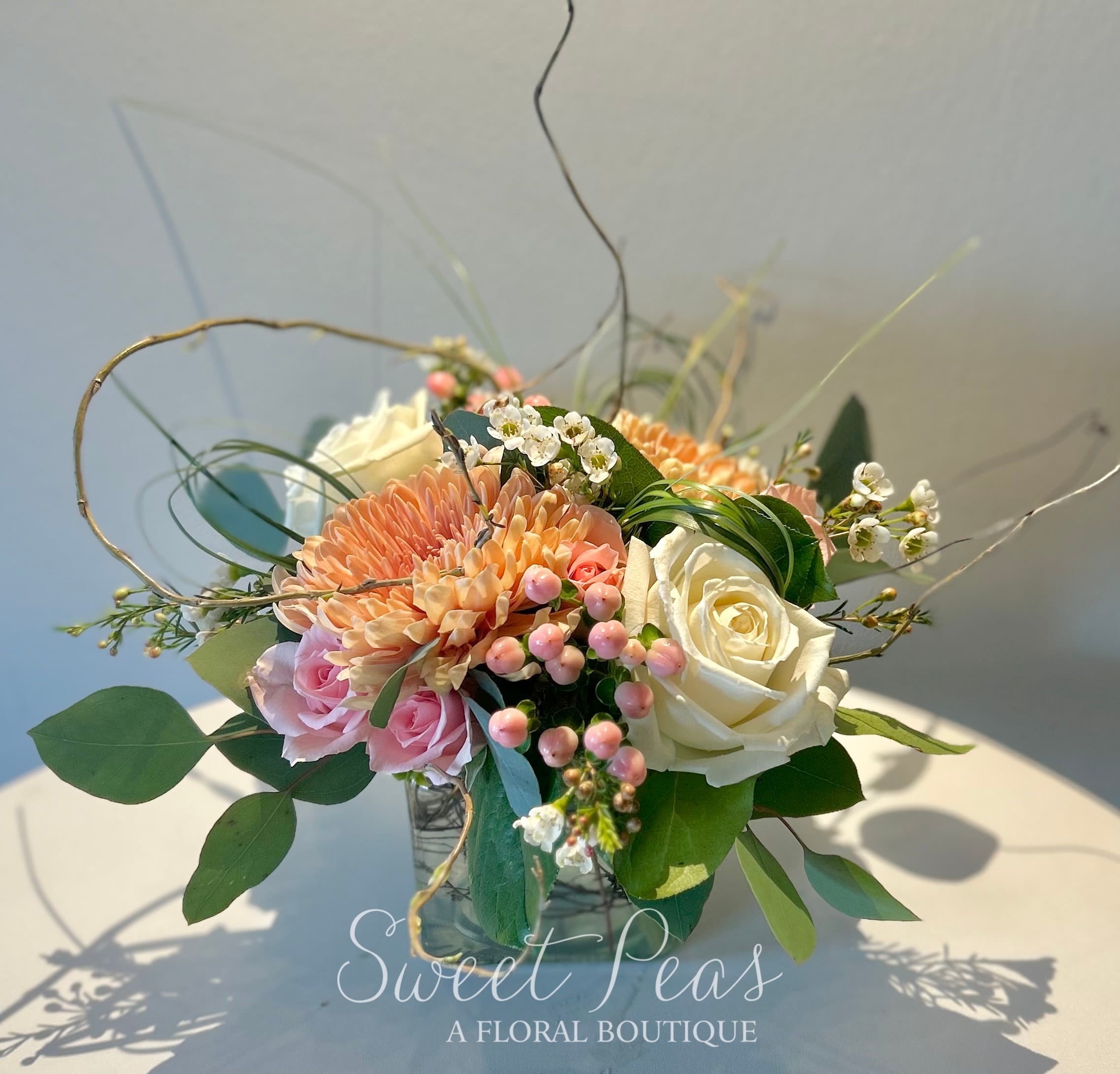 Peach and white rose bouquet with pink blooms in a glass vase