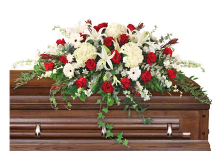 Red and white floral spray on a wooden casket