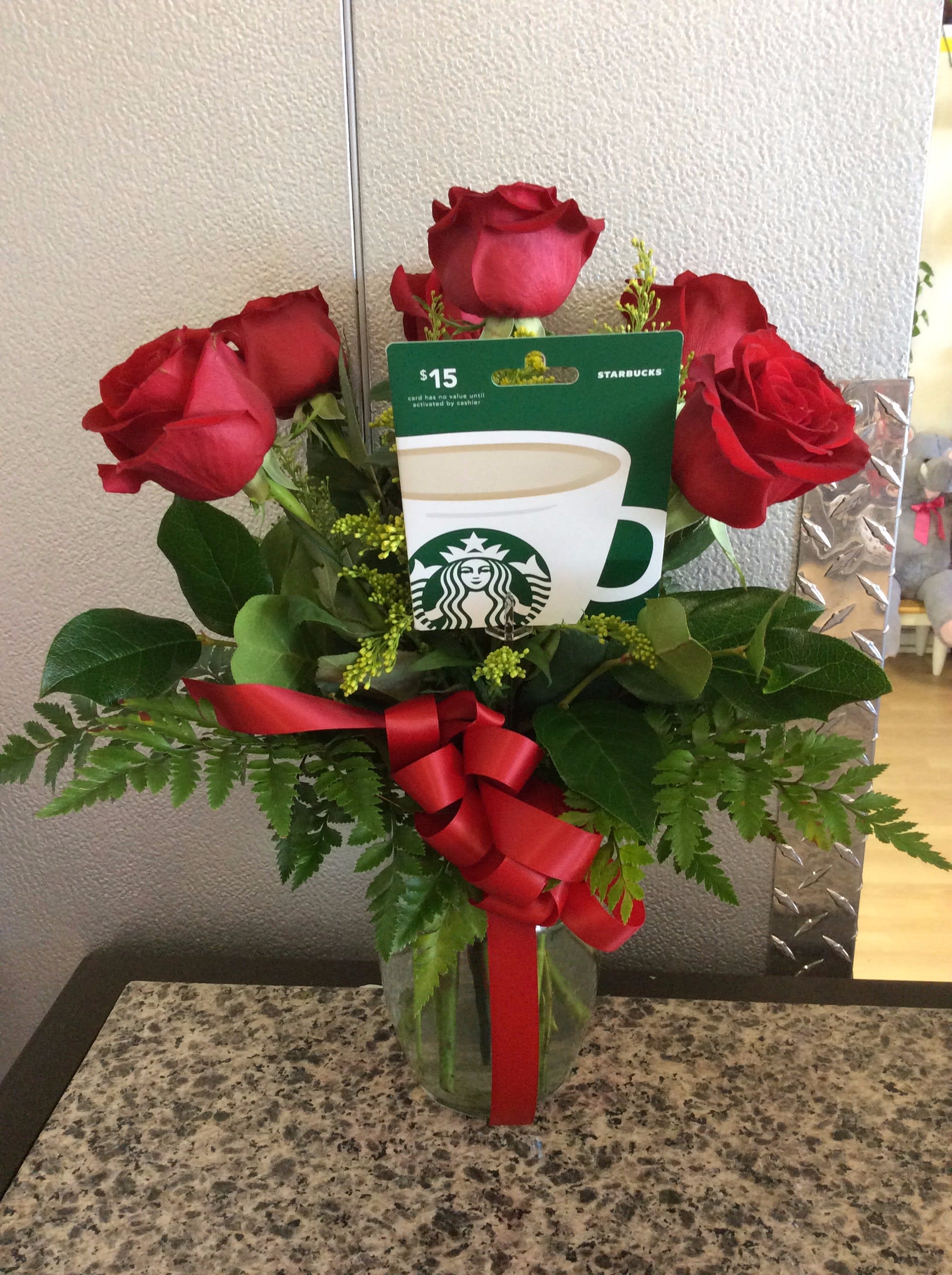 Red roses in a glass vase with a Starbucks gift card and red ribbon