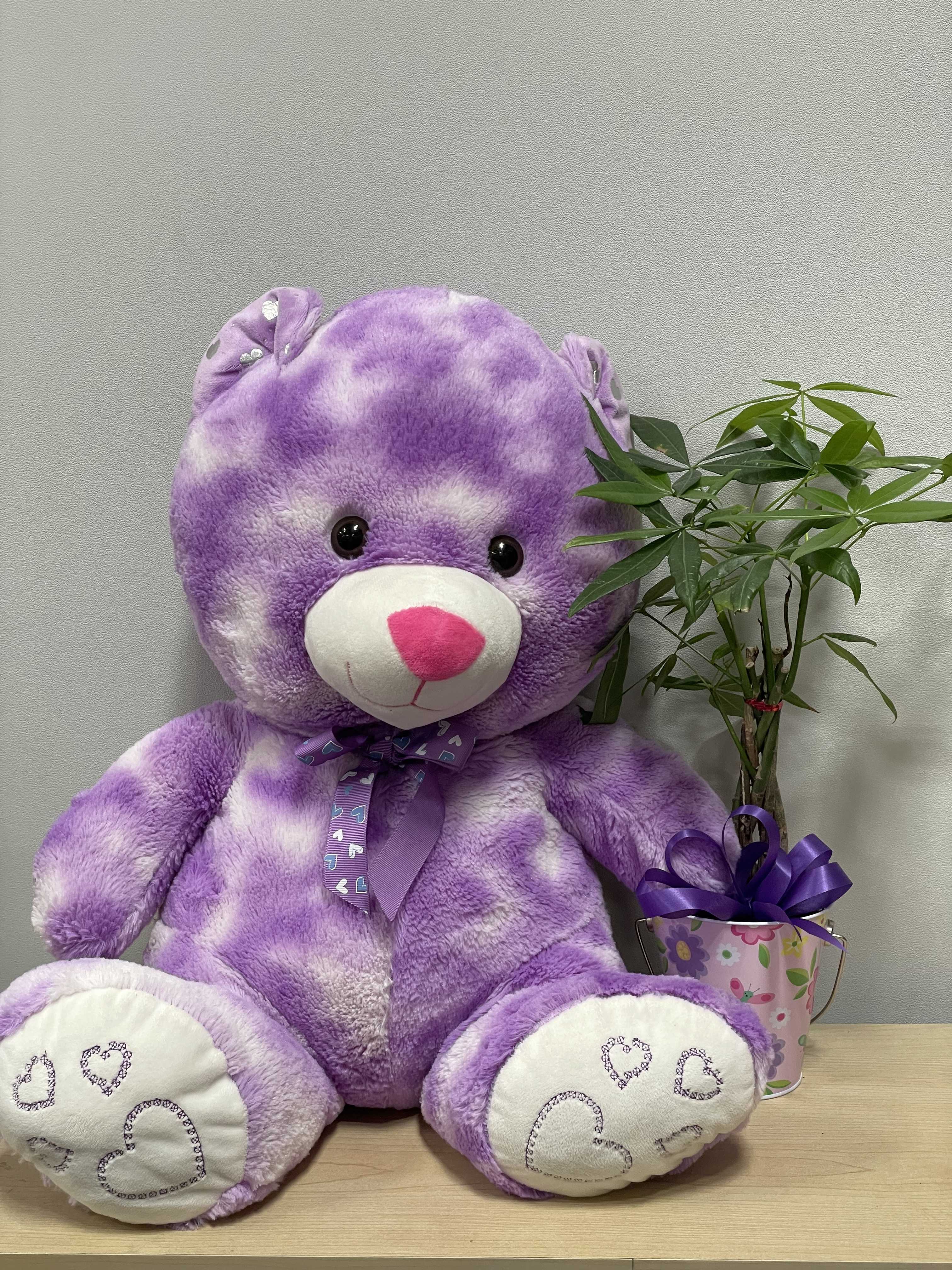 Purple teddy bear beside a small potted plant in a decorated bucket