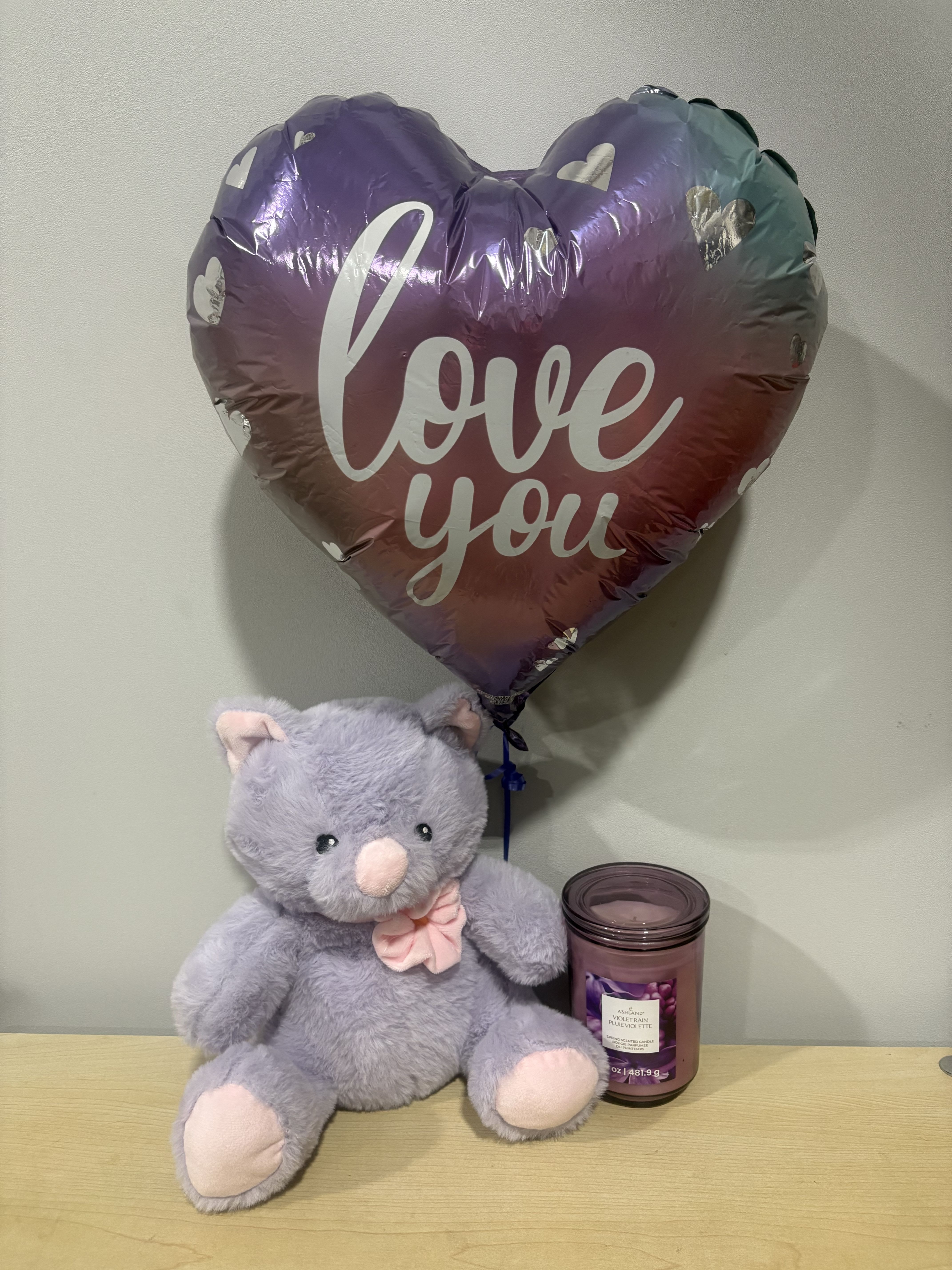 Heart-shaped "love you" balloon with a plush teddy bear and candle