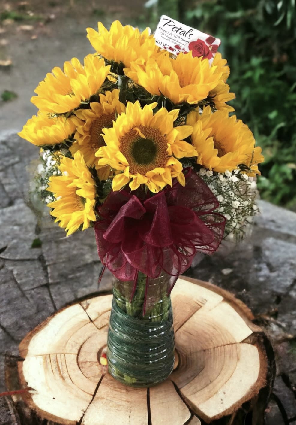Seasonal Sunny Sunflower Vase by Petals - Brighten someone's day with a stunning arrangement featuring a large, clear glass vase overflowing with seasonal sunny sunflowers, a delicate touch of baby's breath, lush greens, a decorative bow, and your personalized message card. Please note that sunflower styles, colors, and sizes may occasionally vary based on daily availability. If you have any questions, feel free to call me directly at 401-828-0701. Thank you, Cheryl.