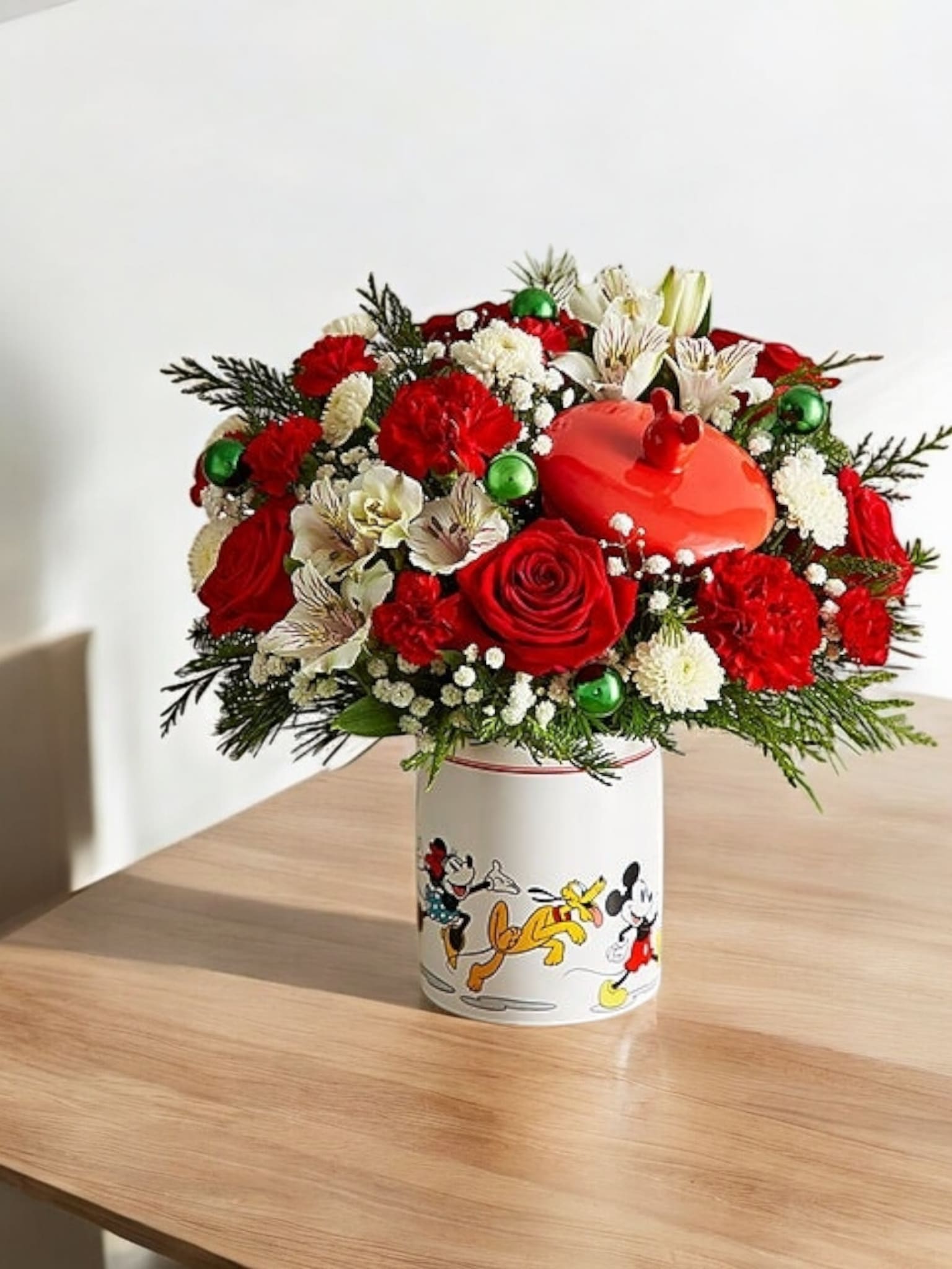 Red and white floral arrangement in a Mickey Mouse container