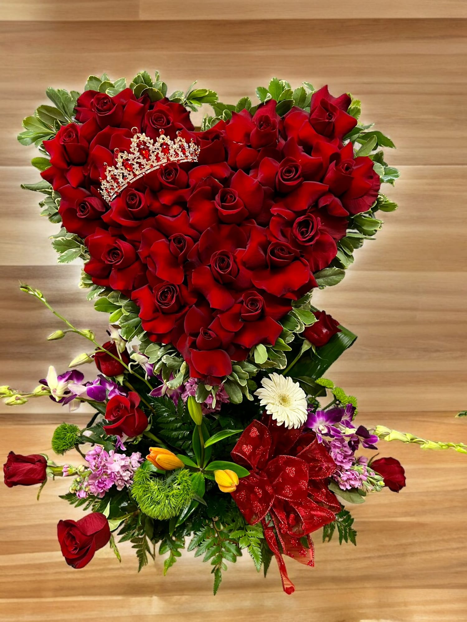 Heart-shaped bouquet of red roses with a jeweled tiara and ribbon