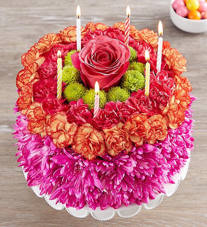 Round floral cake with a rose center and lit candles
