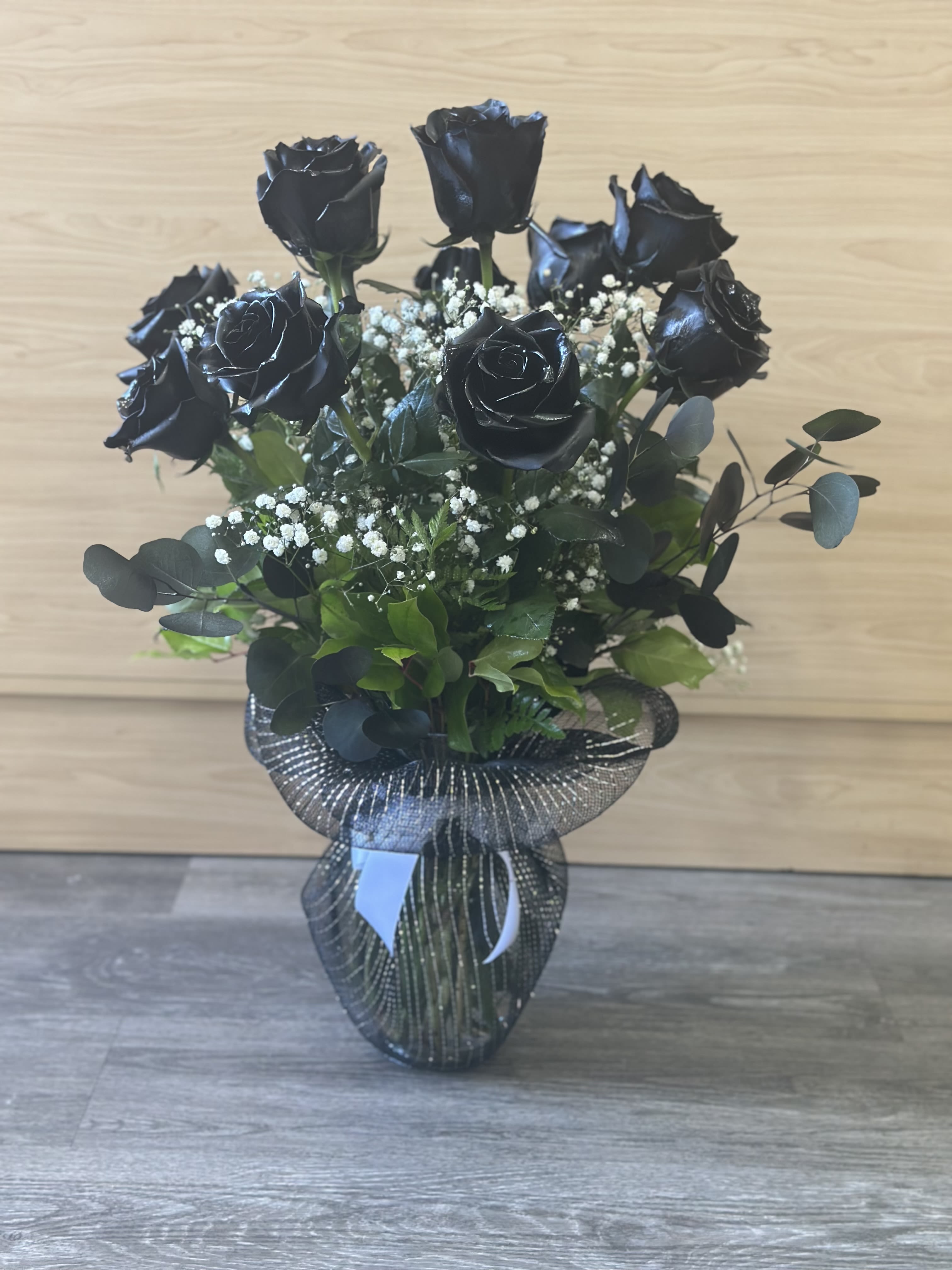 Black roses  - Long stem black roses arranged in a tall vase with greens and filler.  Netting around the vase and a bow.  