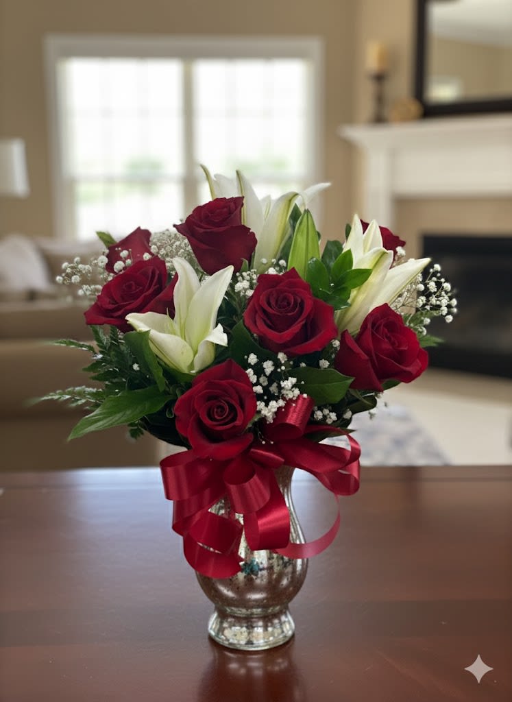 Bouquet of red roses and white lilies in a glass vase with a red ribbon