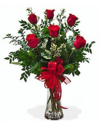 Red roses arranged in a clear glass vase with a red ribbon