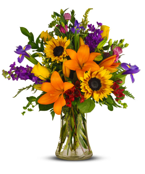 Colorful bouquet of lilies, sunflowers, and purple flowers in a glass vase