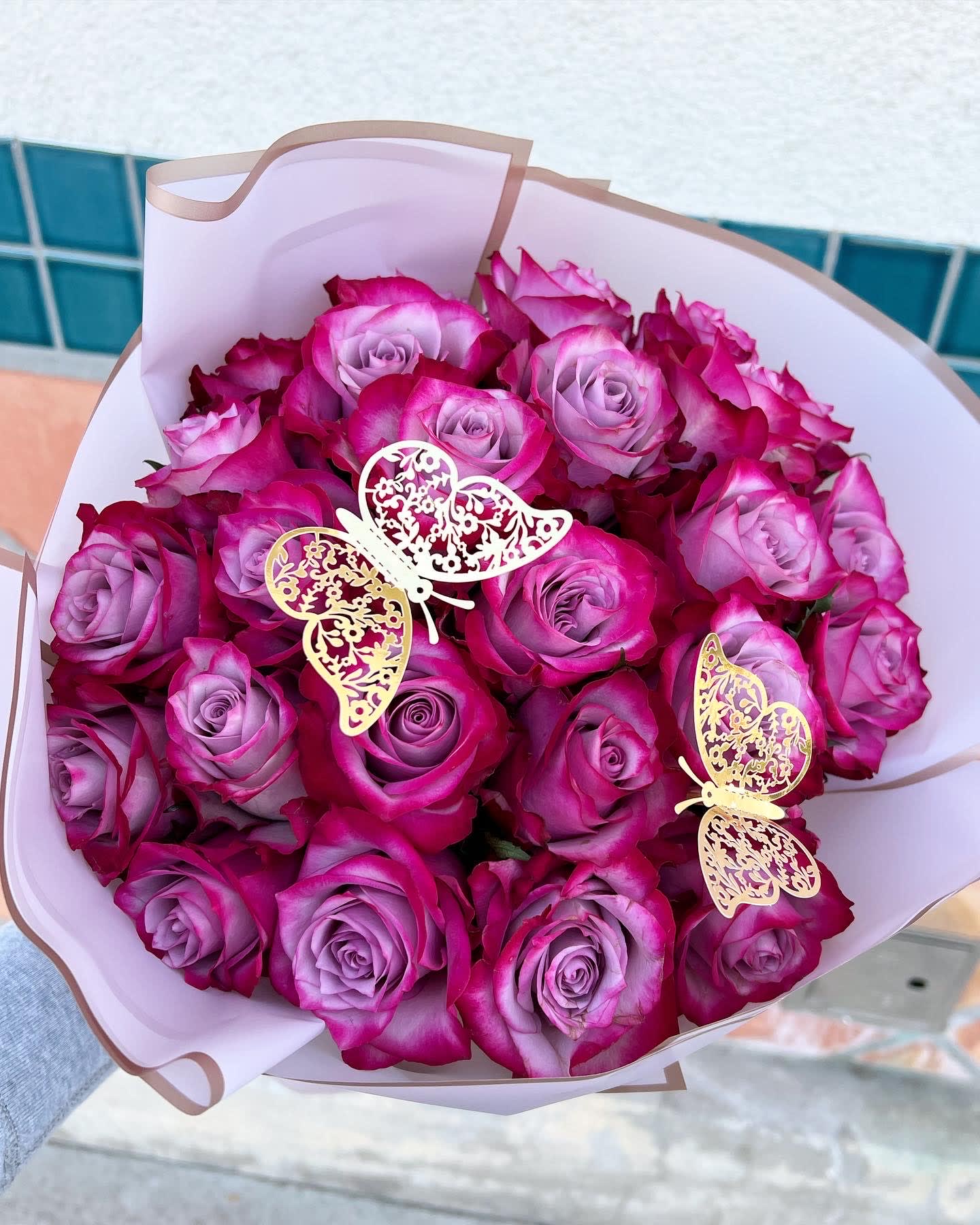 Bouquet of pink and lavender roses with butterfly decorations