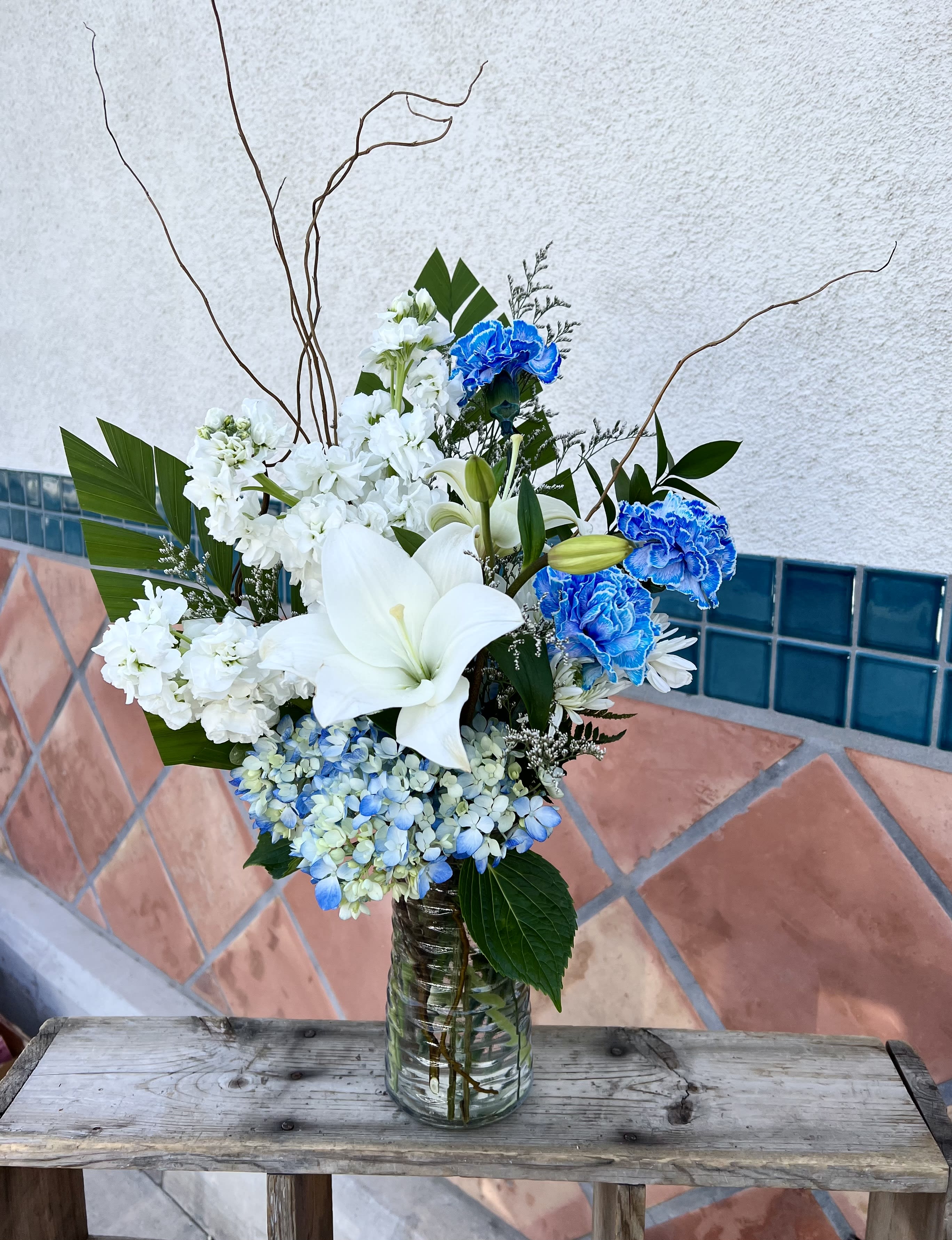 White lilies and blue carnations in a glass vase