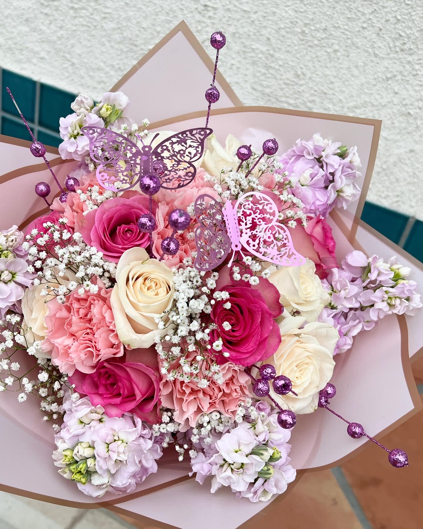 Pink and cream rose bouquet with lilac flowers and butterfly picks