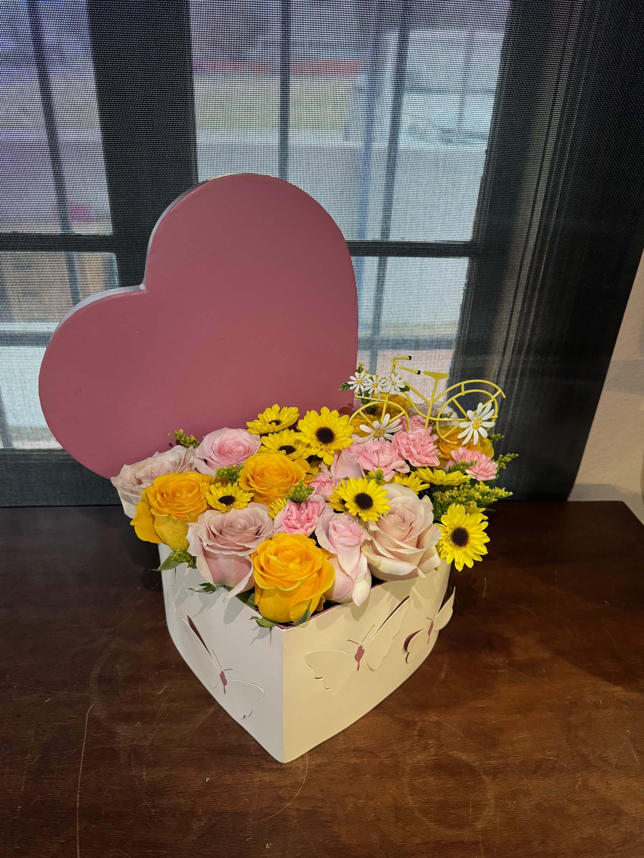 Heart-shaped box of pink and yellow flowers
