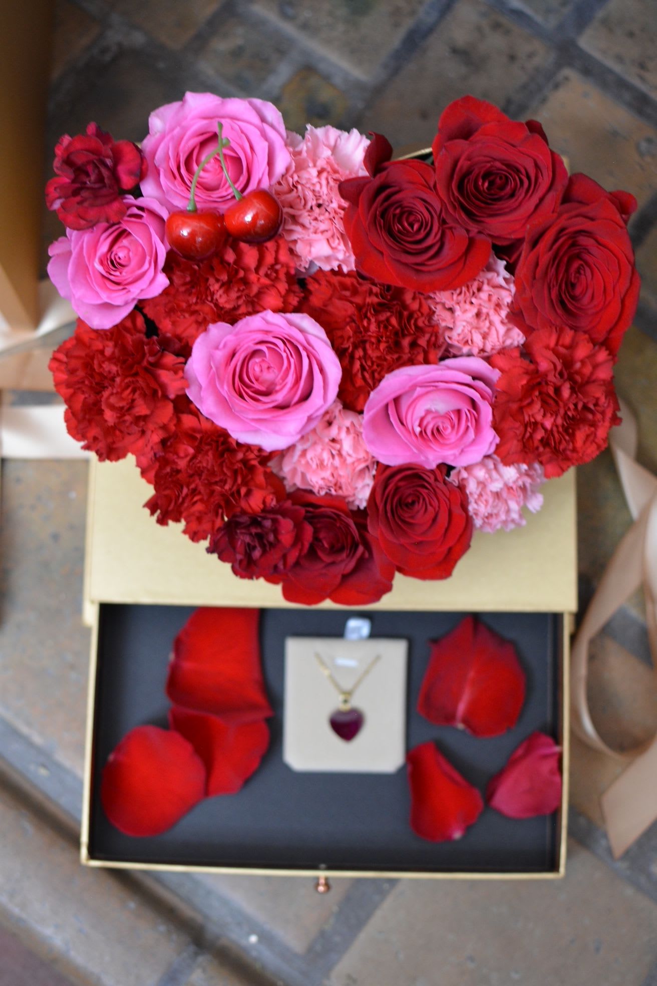 A Love to Hold - A heart-shaped acrylic jewelry box filled with fresh flowers, cradling a timeless necklace inside—designed to be held close and remembered always.  Heart-Shaped Gold-Plated Rose Petal Necklace Delicate and timeless, this gold-plated necklace features a  heart-shaped pendant cradling a real preserved rose petal at the center. Each petal is carefully selected and sealed, making every piece truly one of a kind—no two are ever exactly alike.  Lightweight and effortlessly wearable, this necklace captures the beauty of love in its most natural form: imperfect, fleeting, and deeply meaningful. Designed to be worn daily or gifted as a keepsake for someone special.  Details: Gold-plated heart-shaped pendant (25mm) 1.5mm gold-plated chain, 17 inches long Real preserved rose petal One-of-a-kind piece Handmade with care