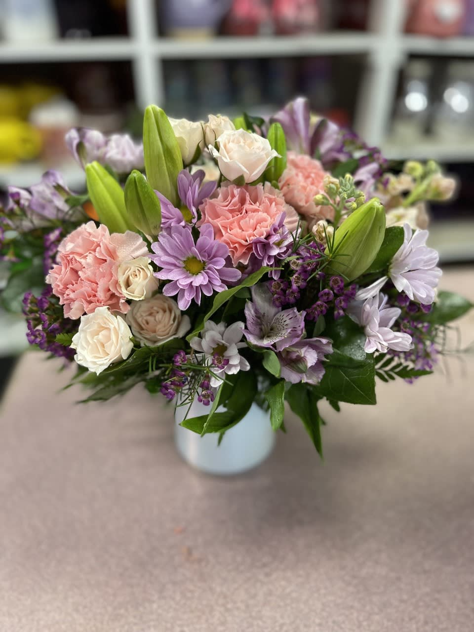 Mixed pink and lavender flowers arranged in a white vase