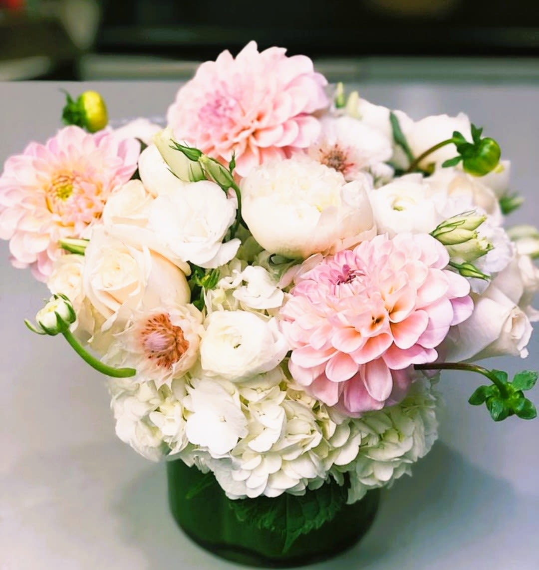 Pink and white flowers arranged in a green glass vase