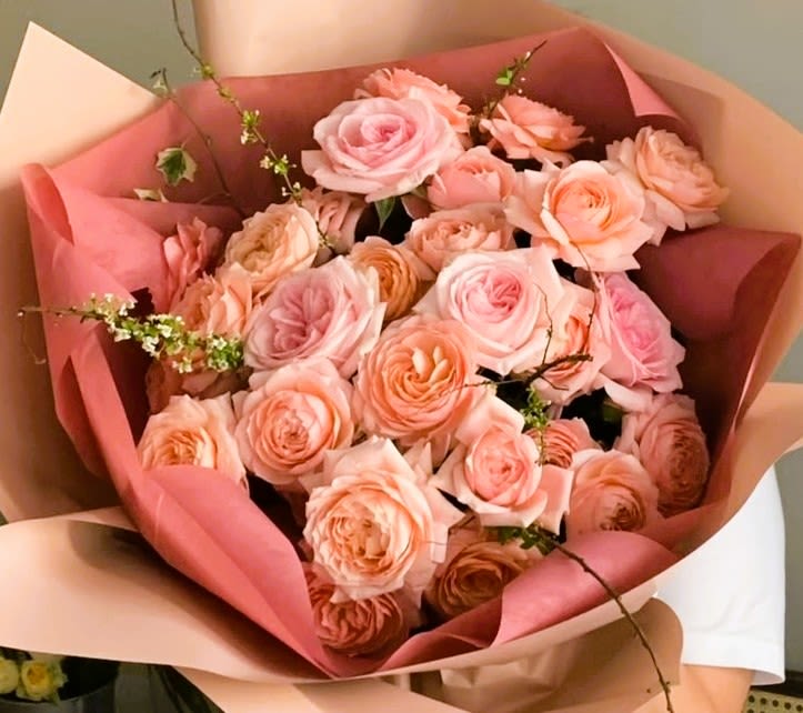 Bouquet of blush and peach roses wrapped in pink paper