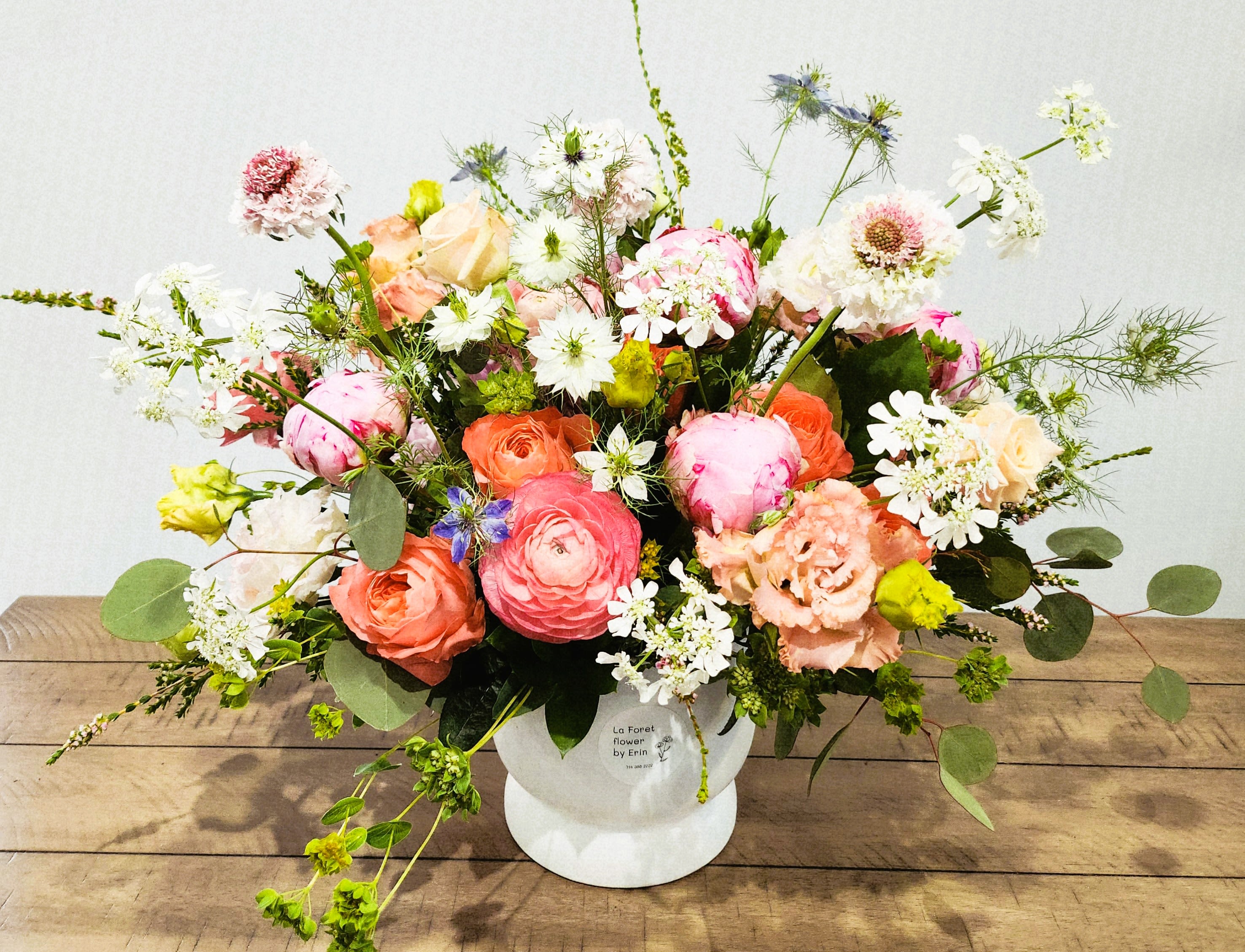 Mixed bouquet of pink, peach, and white flowers in a white vase