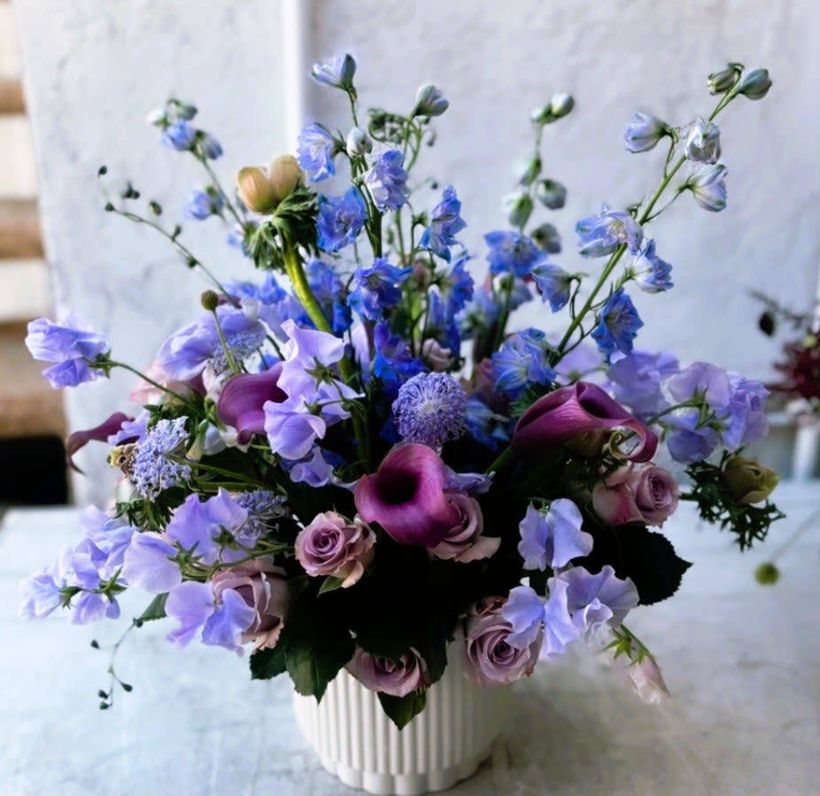 Purple and blue mixed bouquet in a white vase