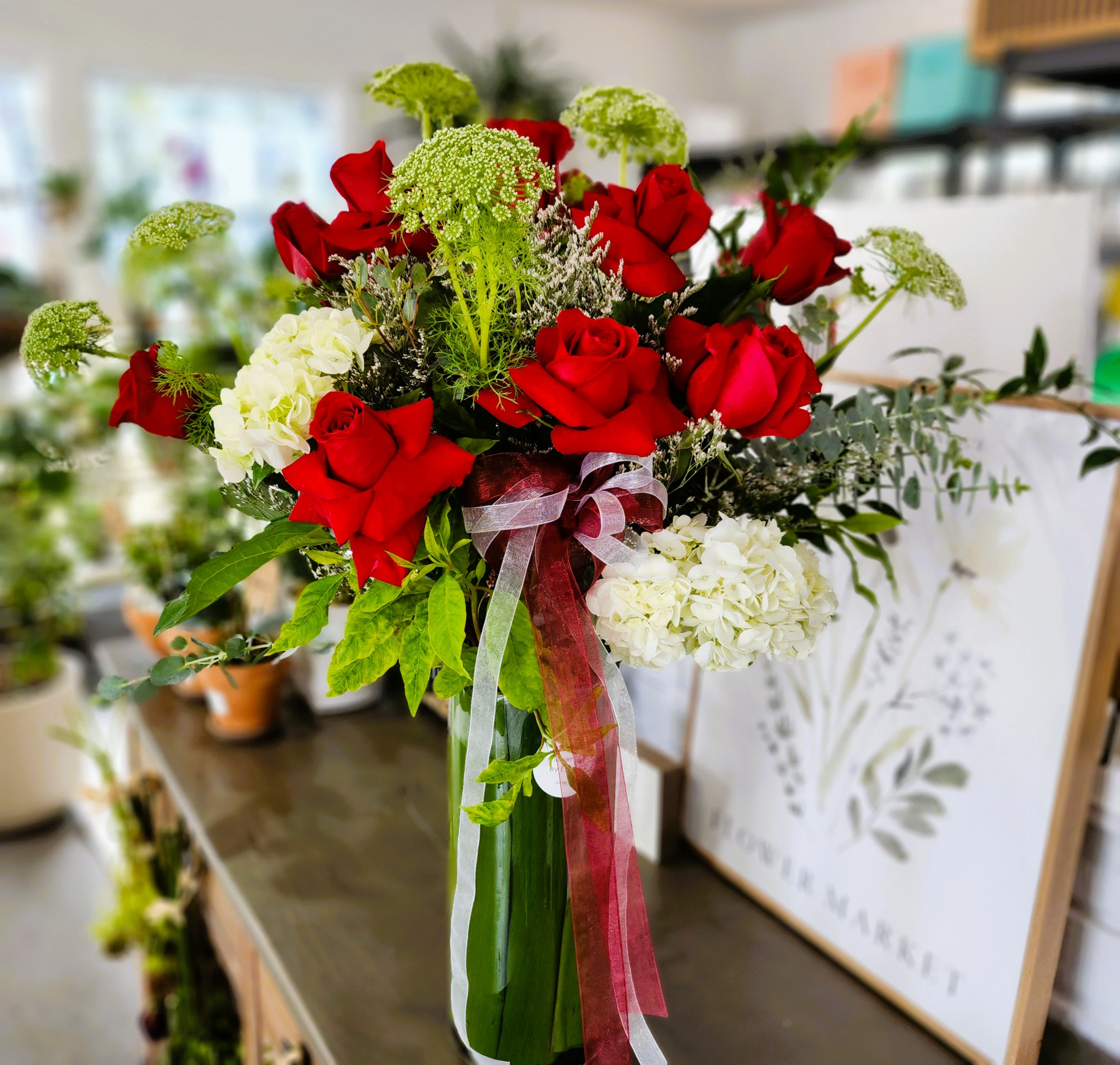 Bouquet of red roses and white hydrangeas with ribbon in a glass vase