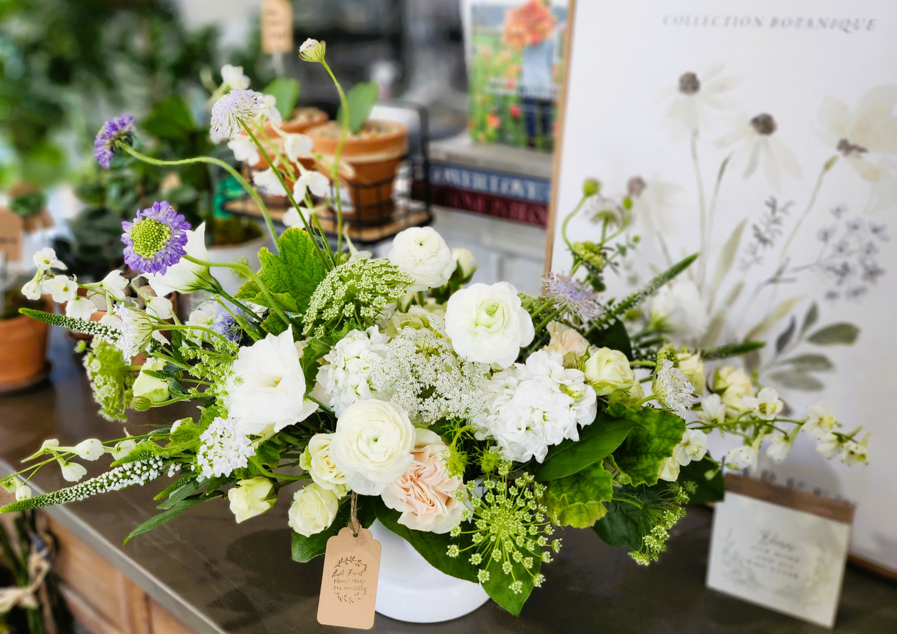 White and pale green floral arrangement in a white container