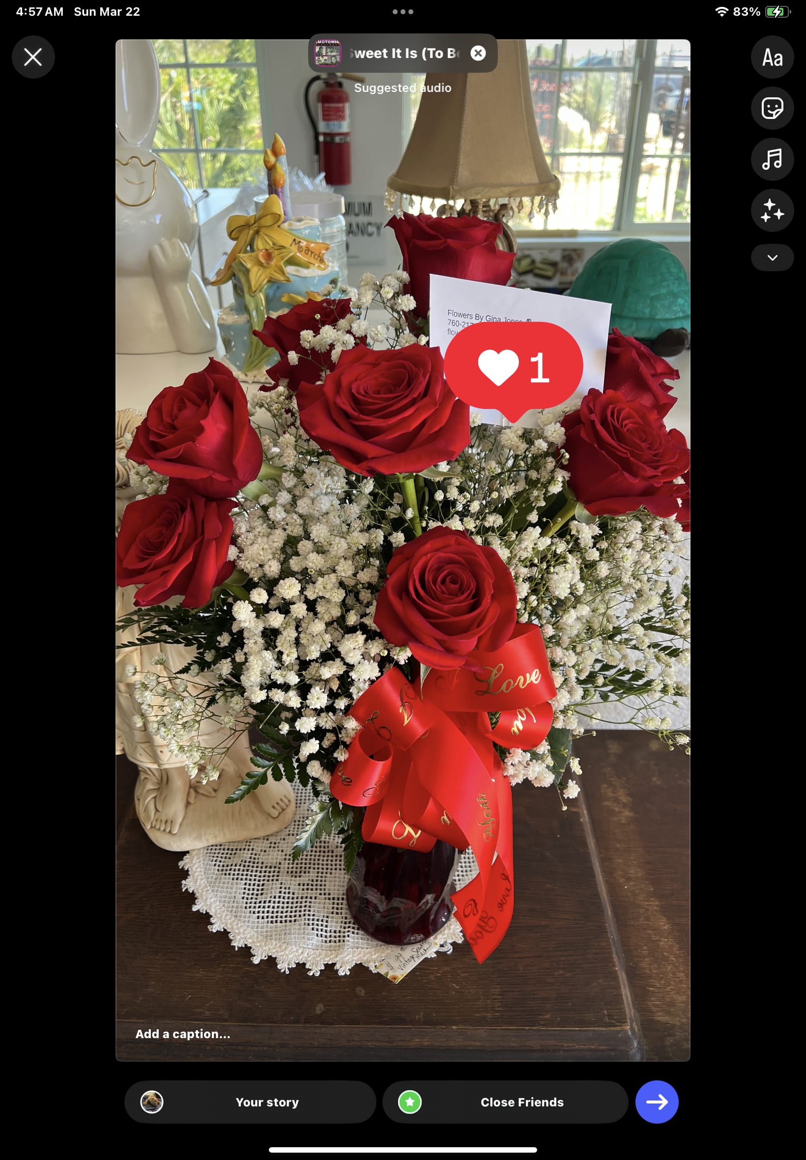 Arrangement of red roses and white filler flowers in a red glass vase with a red love ribbon