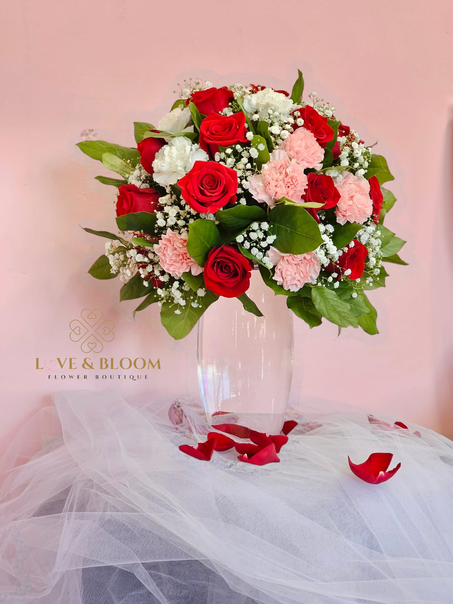 Red and pink rose bouquet in a clear vase with white filler flowers