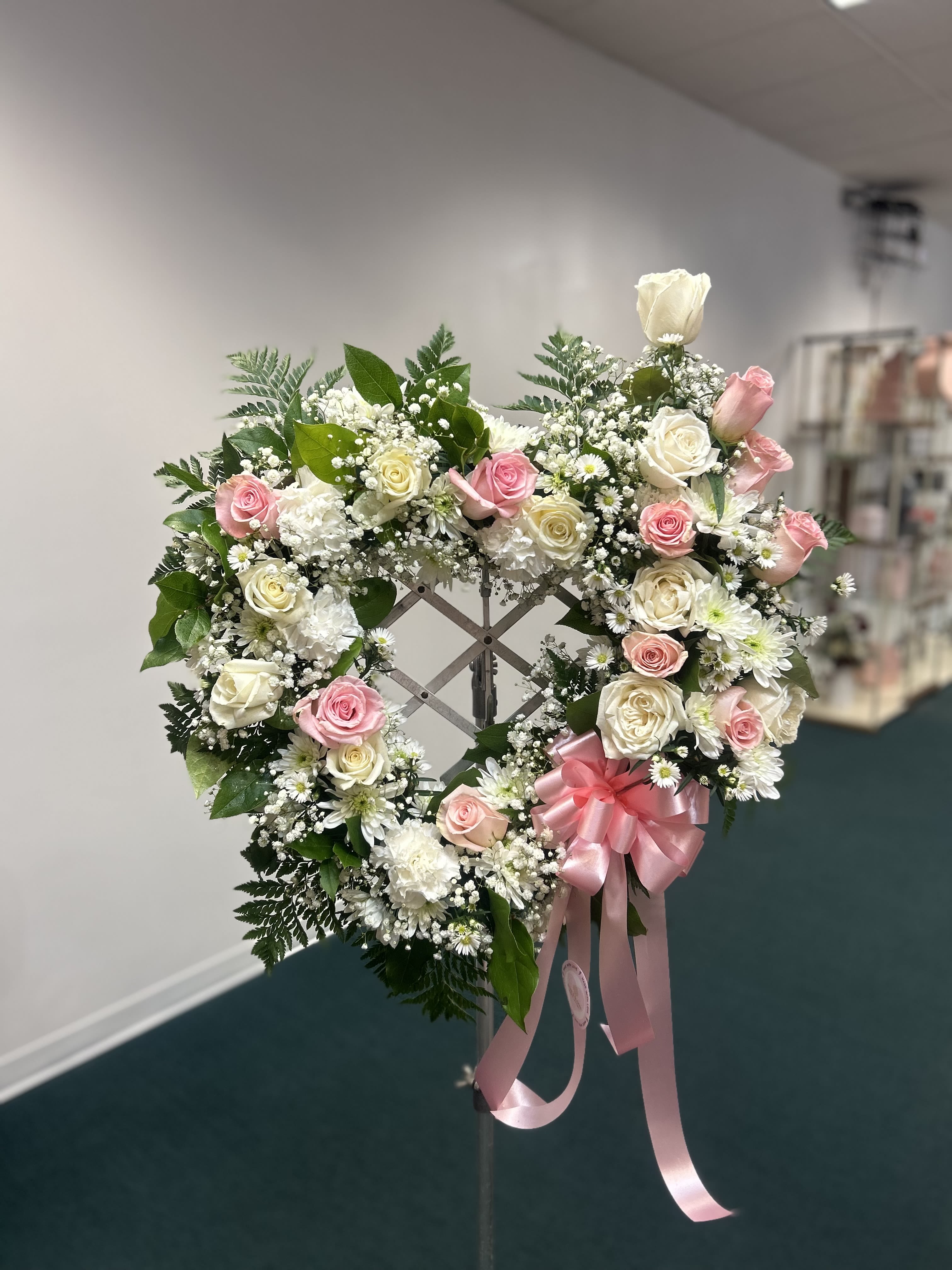 Heart-shaped wreath of pink and white roses with a pink ribbon