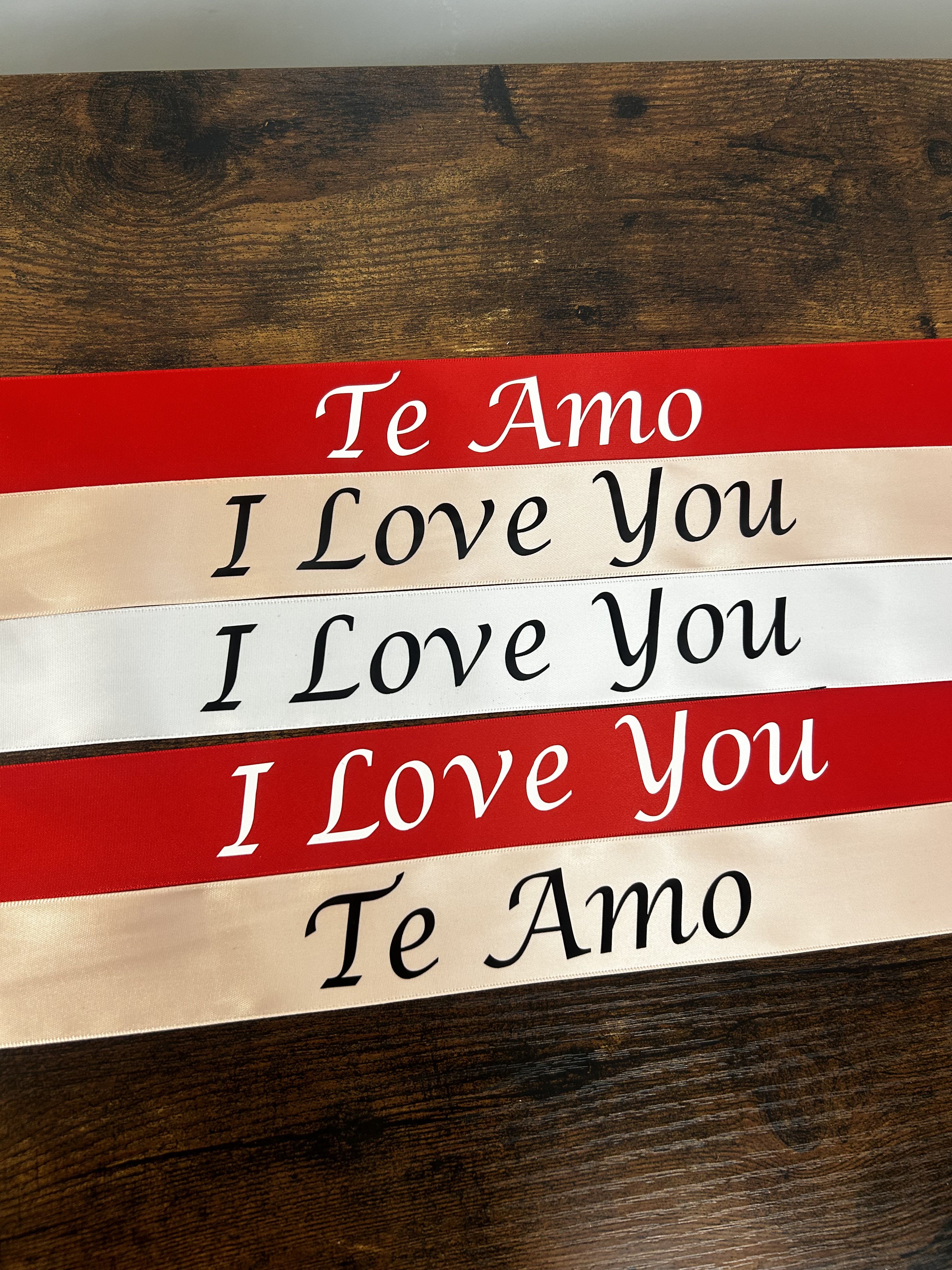 Stacked red and ivory ribbons printed with "Te Amo" and "I Love You"