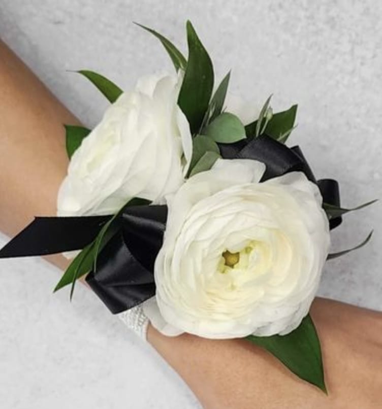 White ranunculus wrist corsage with black ribbon and green leaves