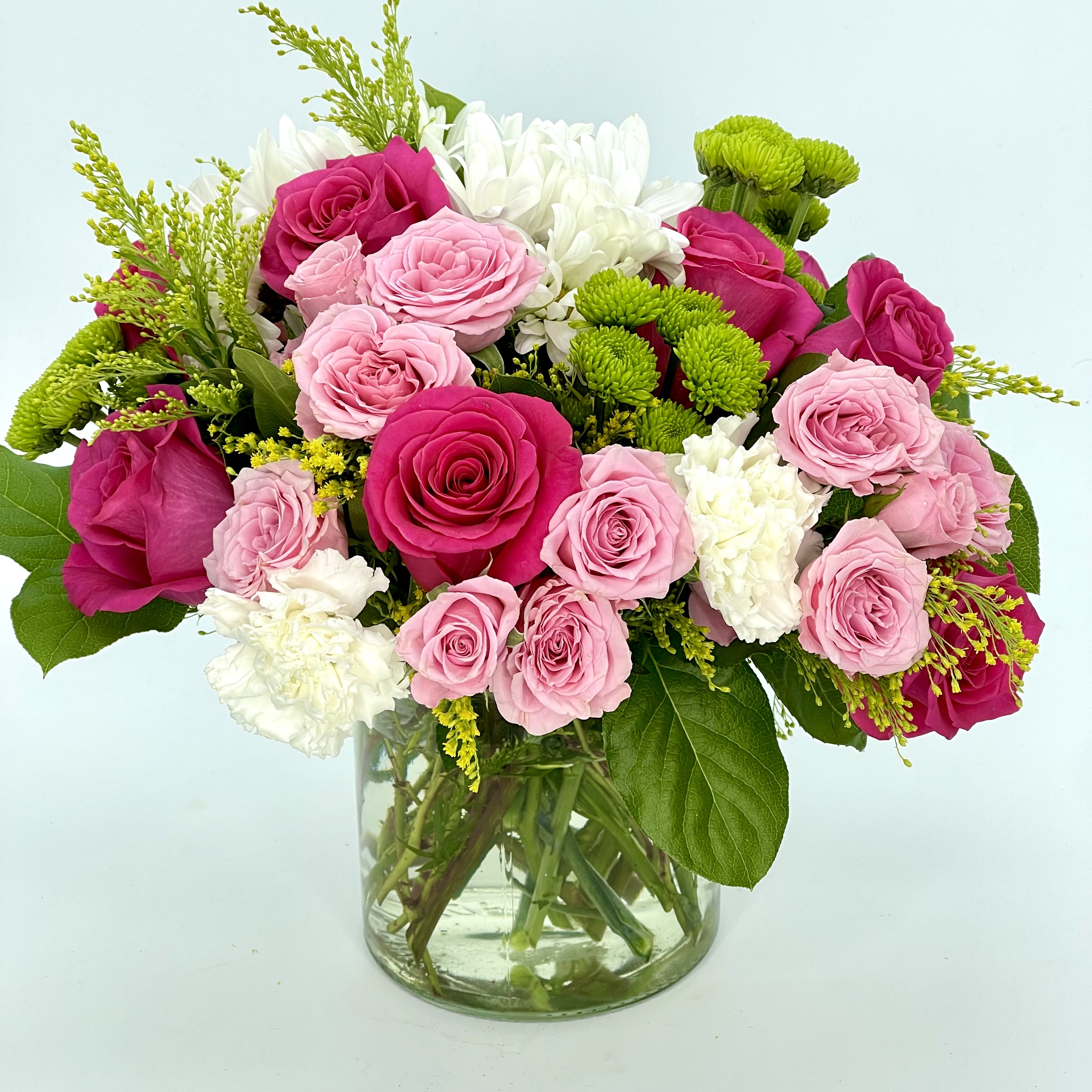 Pink and fuchsia roses with white and green blooms in a clear glass vase