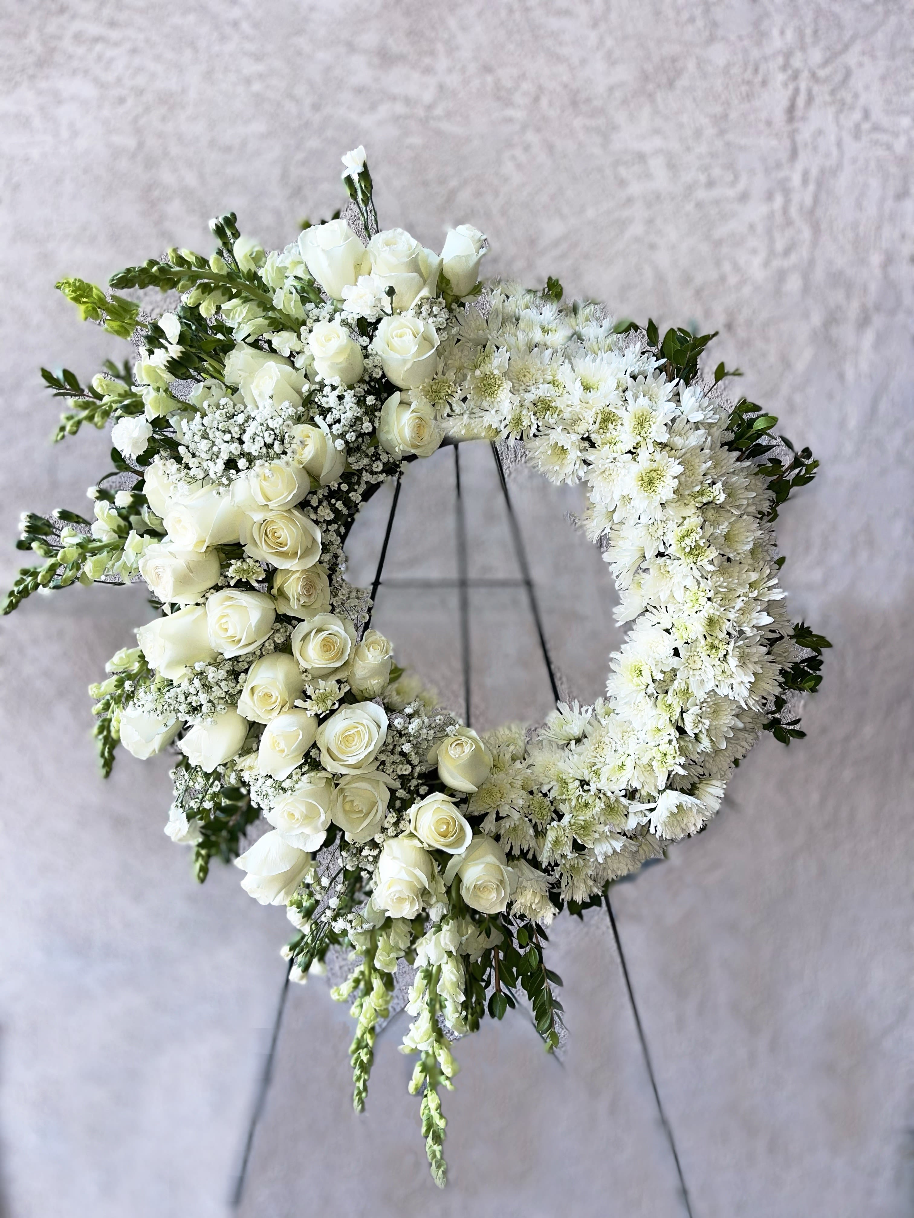 Large white rose and mum wreath with cascading blooms on a standing easel