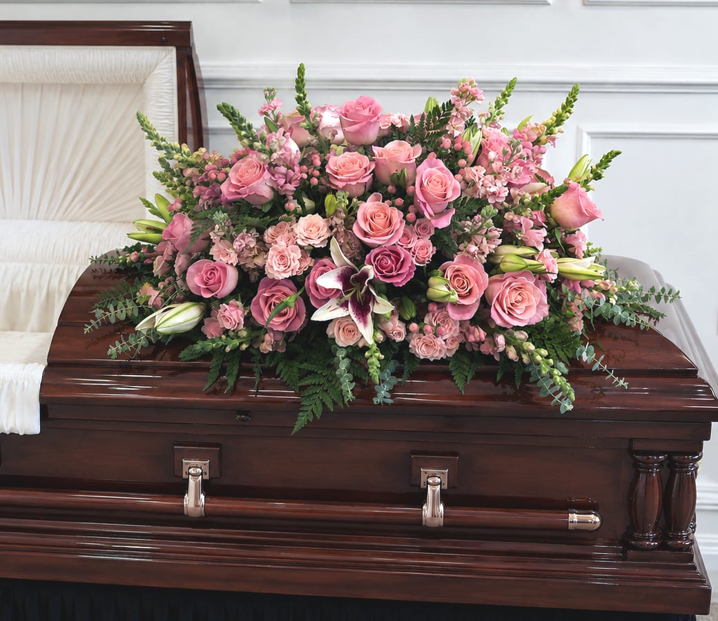 Pink rose casket spray with lilies and greenery