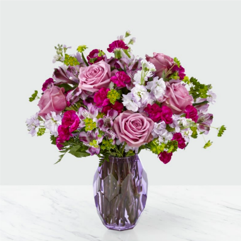 Pink and white mixed bouquet in a purple glass vase