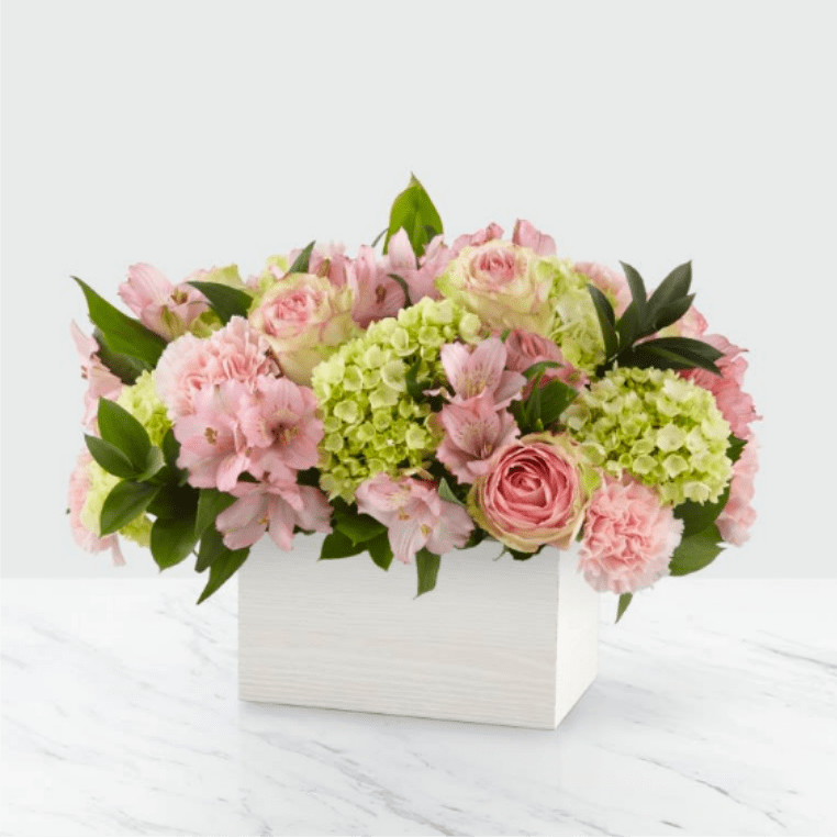 Pink and green floral arrangement in a white box