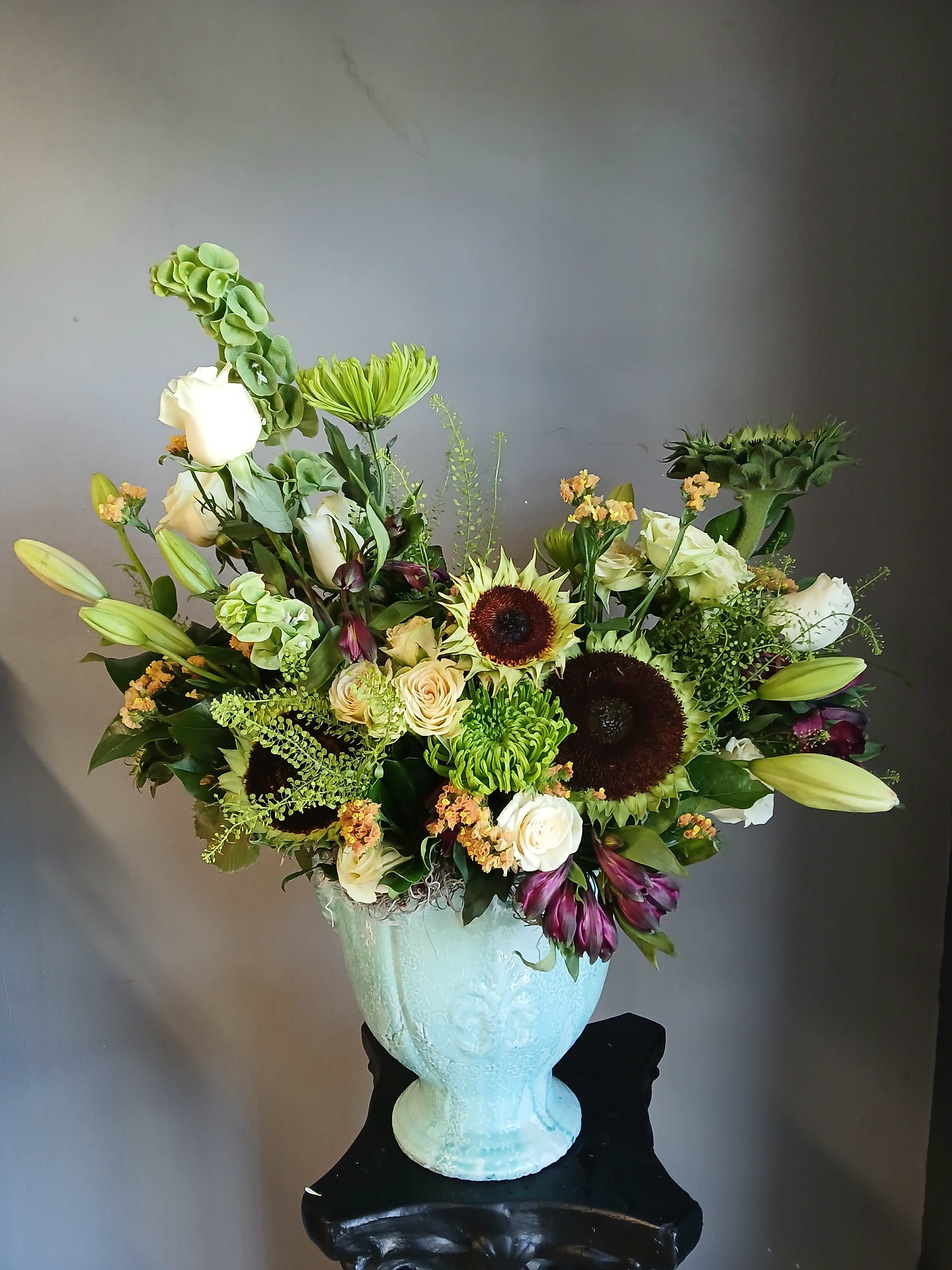 Large mixed flower arrangement in a pale blue vase