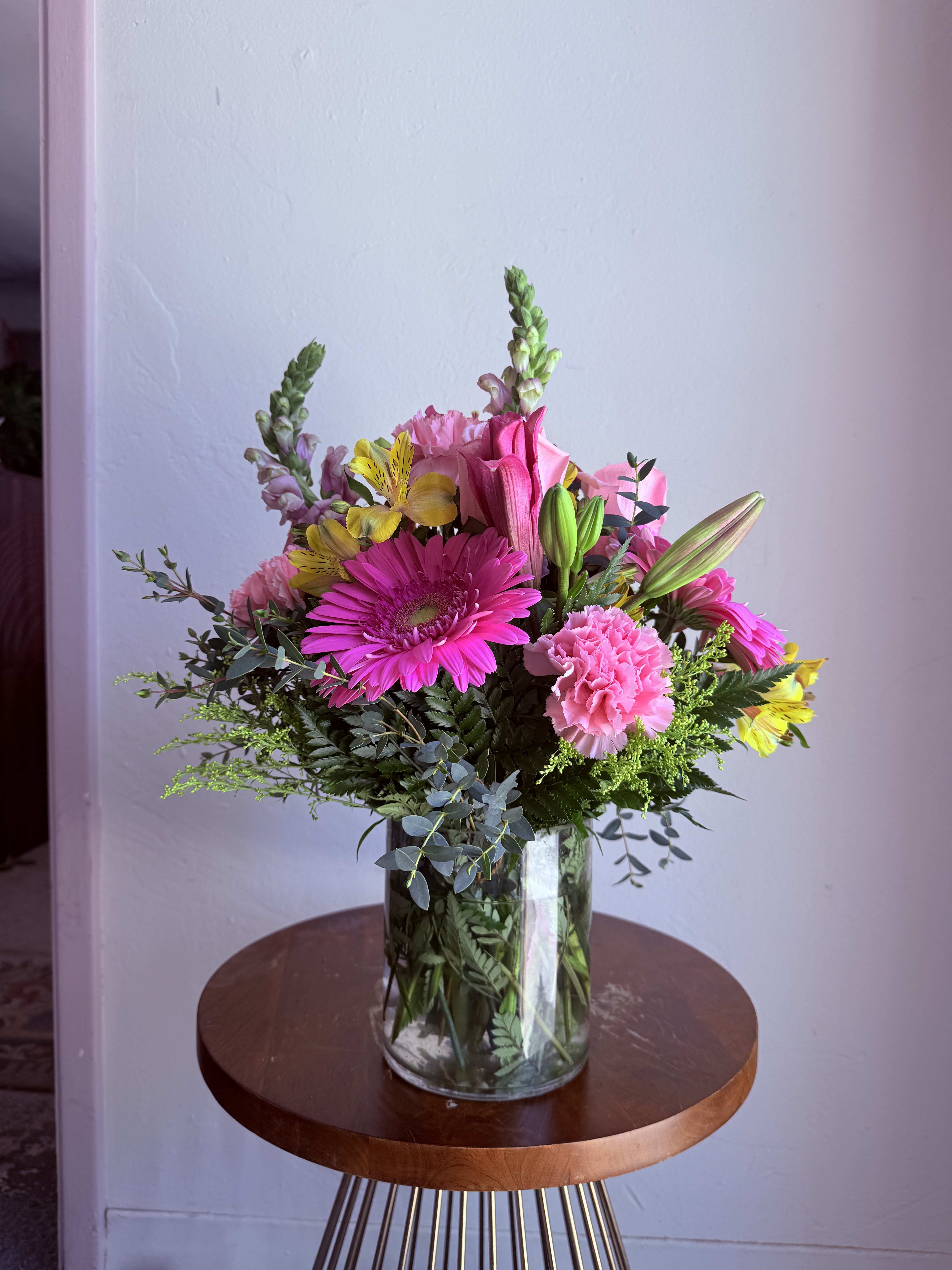 Mixed bouquet of pink and yellow flowers in a clear glass vase